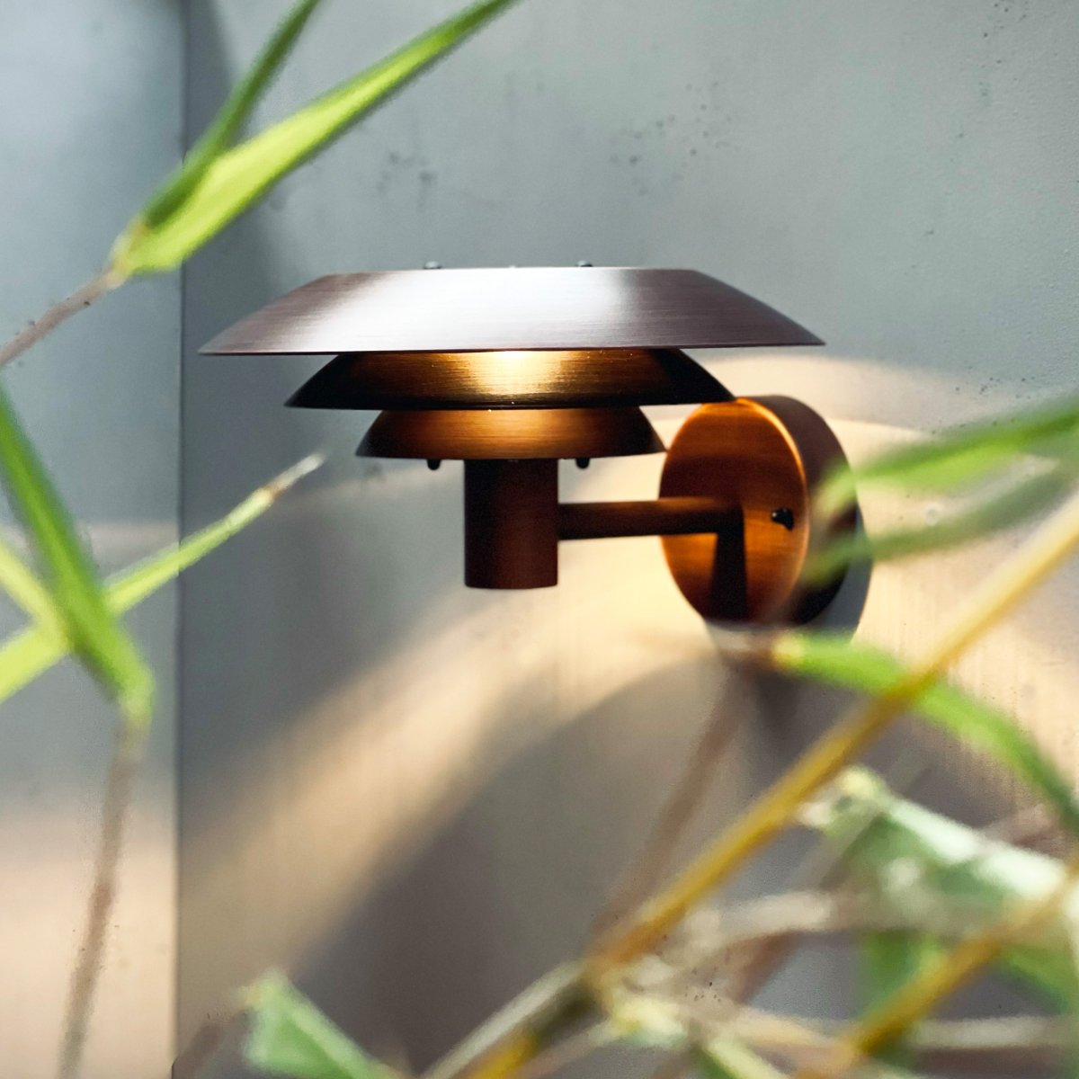 DL25 Kopper utendørslampe Fra Dyberg Larsen - Med sina tre ikoniska lampsk&auml;rmar sprider den ett fascinerande ljus, idealiskt f&ouml;r att skapa en st&auml;mningsfull atmosf&auml;r l&auml;ngs fasaden eller i andra utomhusmilj&ouml;er.