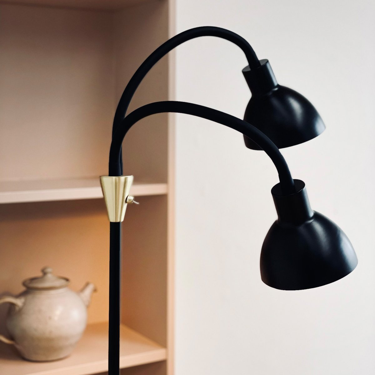 Lilje Svart gulvlampe Fra Dyberg Larsen - Lily golvlampa i svart och m&auml;ssing kombinerar modern design med flexibilitet och funktionalitet.