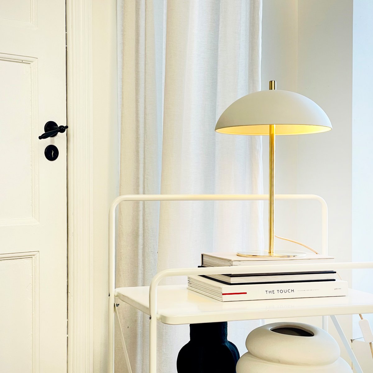 Globus 44cm Messing/beige bordlampe Fra Dyberg Larsen - Lampen er laget av metall og kombinerer en myk beige tone med detaljer i messingfinish, noe som gir et harmonisk og moderne uttrykk.