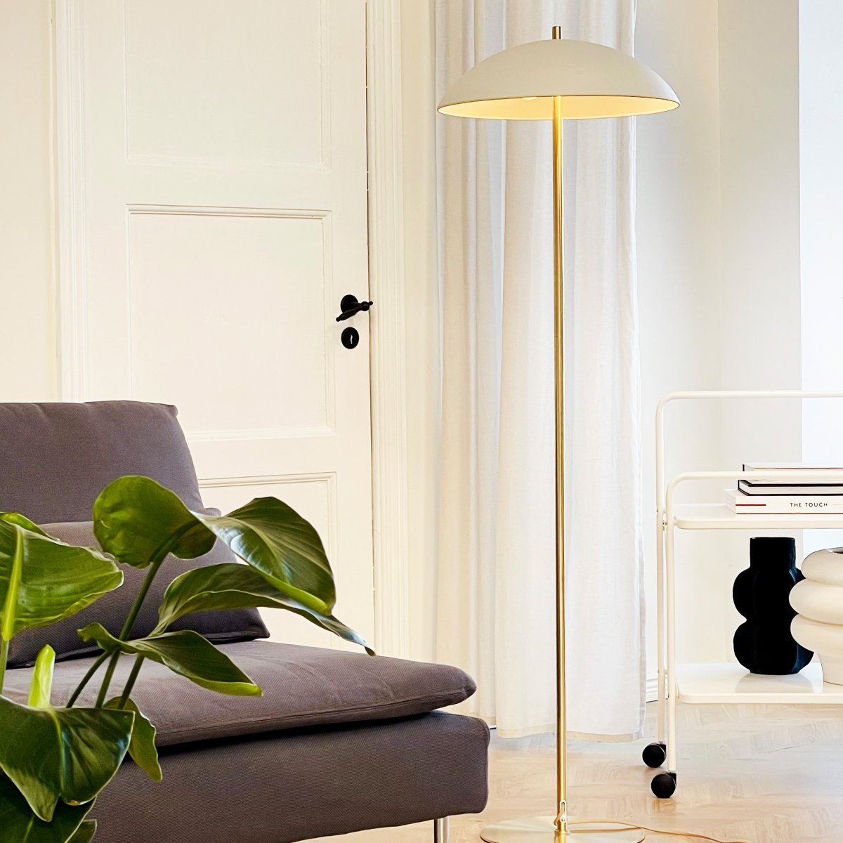 Globus Messing/beige gulvlampe Fra Dyberg Larsen - Lampen er laget av metall og kombinerer en myk beige tone med detaljer i messingfinish, noe som gir et harmonisk og moderne uttrykk.