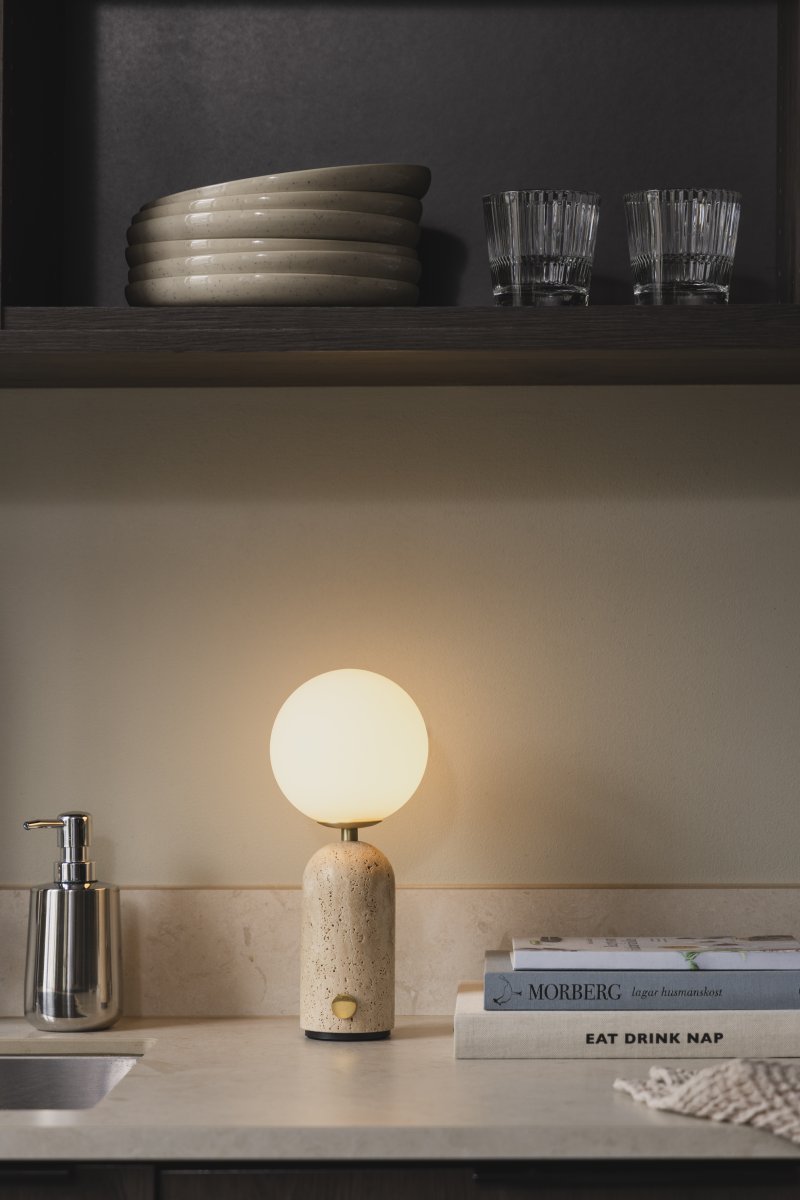 Torrano 28cm Beige travertin bærbar Fra Globen Lighting - Den massive basen i naturstein gir lampen vekt og karakter, mens den runde hvite opalglasskjermen sprer et behagelig lys.