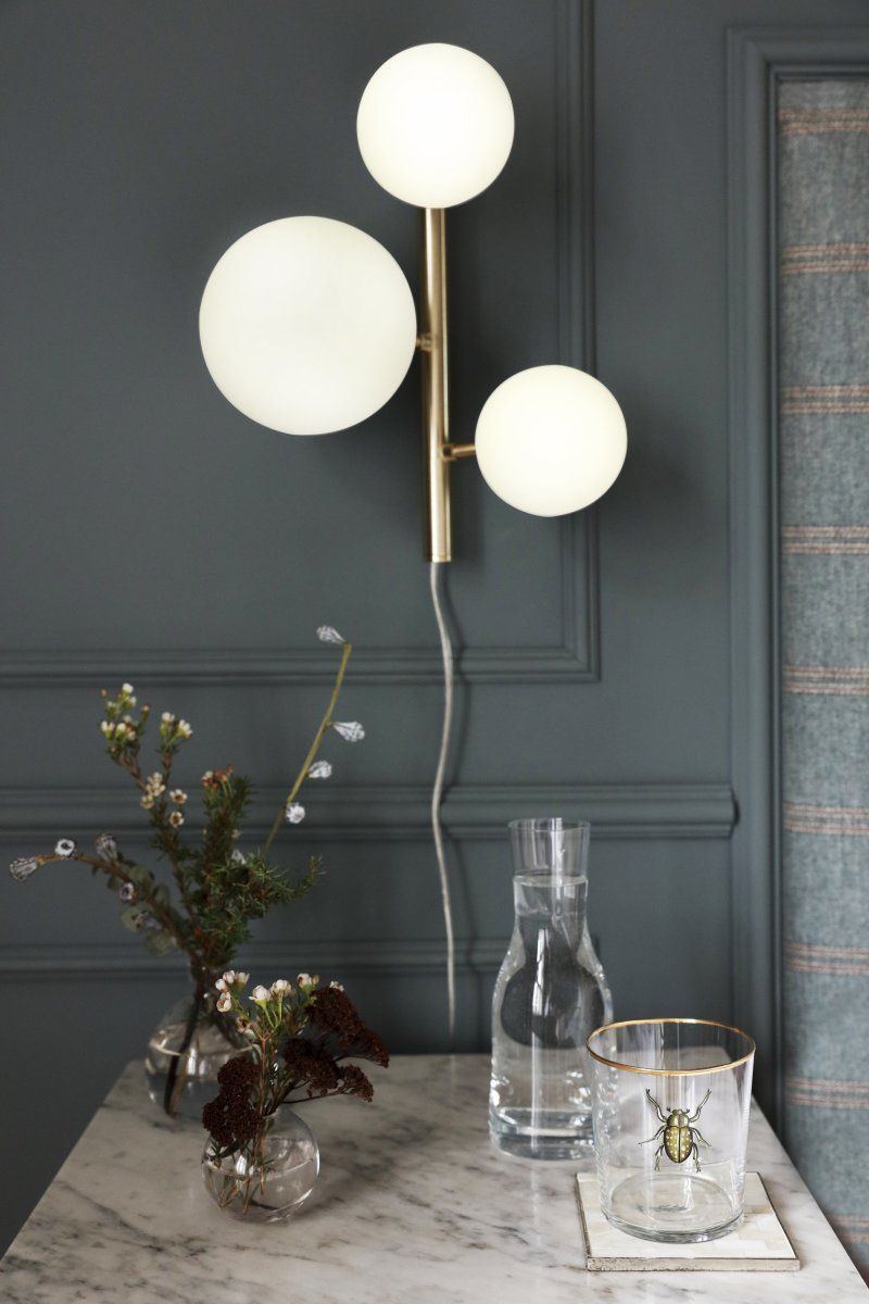 Molekyl 36cm Matt messing vegglampe Fra Aneta Lighting - Den er laget av metall med en elegant matt messingfinish og har opalhvite glassskjermer som sprer et mykt og behagelig lys.