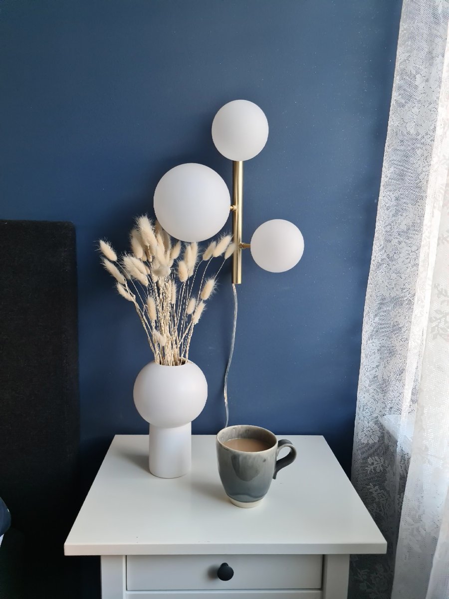 Molekyl 36cm Matt messing vegglampe Fra Aneta Lighting - Den er laget av metall med en elegant matt messingfinish og har opalhvite glassskjermer som sprer et mykt og behagelig lys.