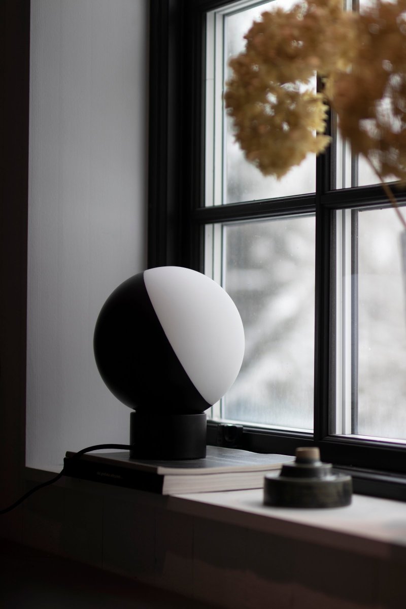 Contur 24cm Svart bordlampe Fra Globen Lighting - Lampen er laget av matt hvitt glass, hvorav halvparten er lasert i matt svart, lyset siver fint gjennom det hvite glasset.