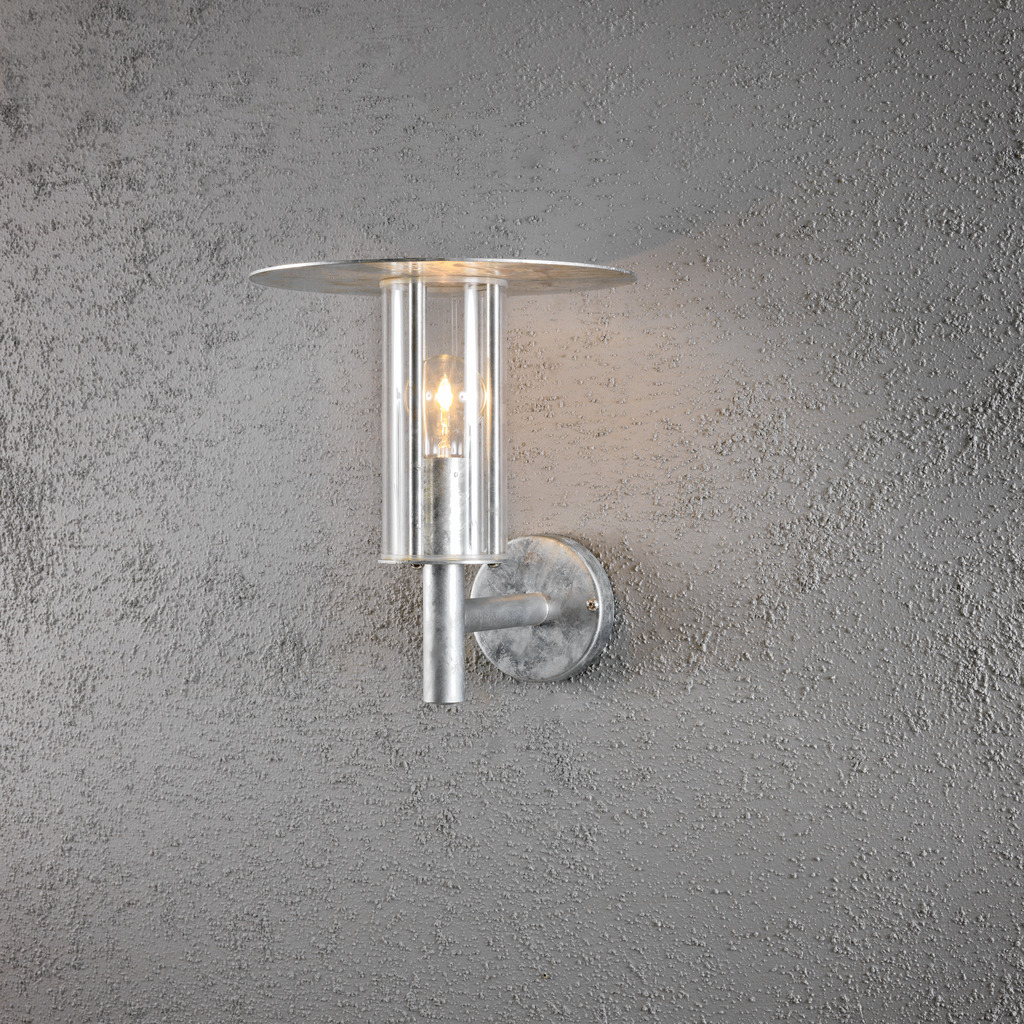 Mode Galvanisert stål utendørslampe Fra Konstsmide - Med sitt minimalistiske design og sylindriske glassbeholder sprer lampen et klart og behagelig lys som lyser opp overbygde innganger og uteplasser.