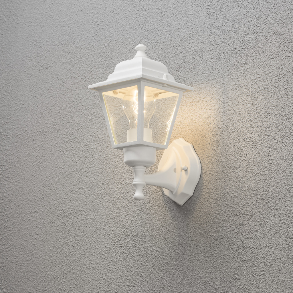 Vägglykta Hvit utendørslampe Fra Konstsmide - Med sitt lanterneformede design og klare glassfelt sprer lampen et varmt og innbydende lys som er perfekt for innganger, uteplasser og gangveier.