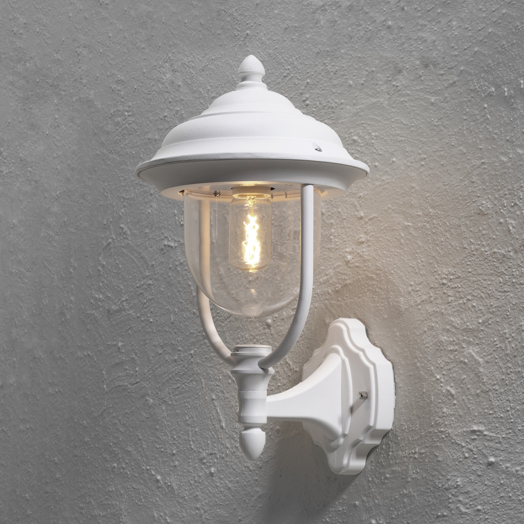Parma Hvit utendørslampe Fra Konstsmide - Med sin vakre form og klare glasskuppel sprer den et varmt og innbydende lys, ideelt for innganger og uteplasser.