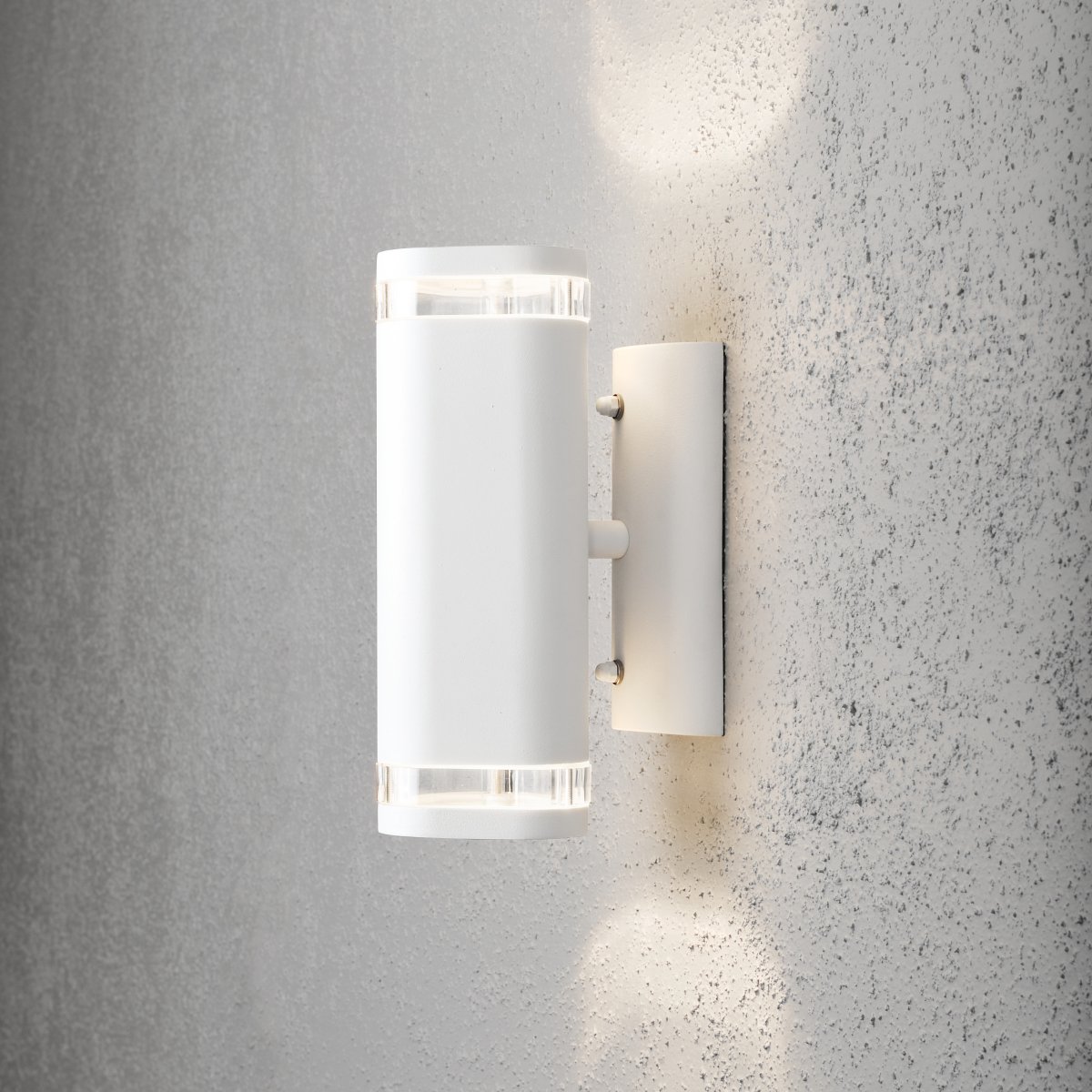 Modena II Hvit utendørslampe Fra Konstsmide - Lyset er rettet b&aring;de oppover og nedover og skaper et dekorativt og effektfullt lysbilde som l&oslash;fter fasaden og gir hagen en innbydende f&oslash;lelse.