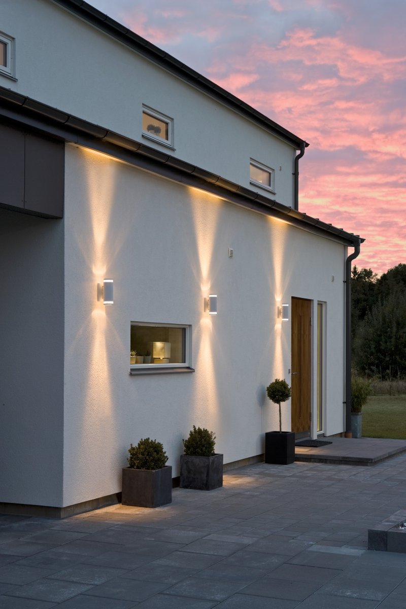 Modena II Hvit utendørslampe Fra Konstsmide - Lyset er rettet b&aring;de oppover og nedover og skaper et dekorativt og effektfullt lysbilde som l&oslash;fter fasaden og gir hagen en innbydende f&oslash;lelse.