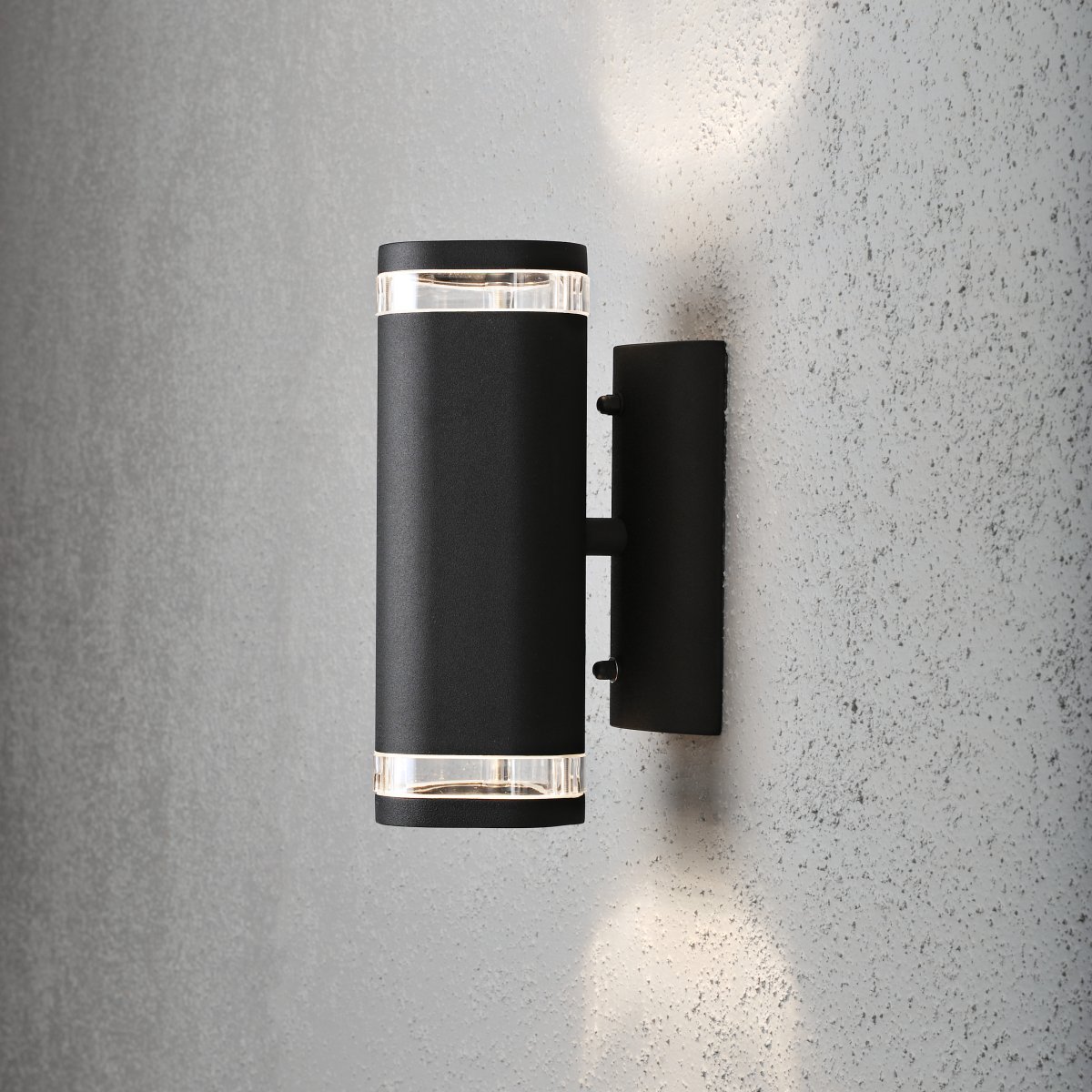 Modena II Svart utendørslampe Fra Konstsmide - Lyset er rettet b&aring;de oppover og nedover og skaper et dekorativt og effektfullt lysbilde som l&oslash;fter fasaden og gir hagen en innbydende f&oslash;lelse.