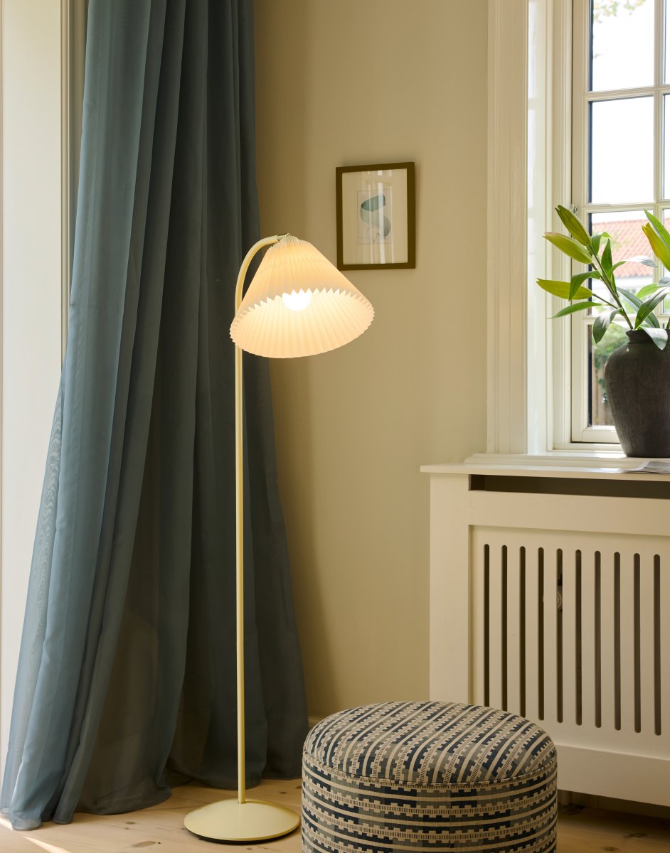 Medina Kremhvit gulvlampe Fra Halo Design - Den kremhvite metallrammen kompletteres av en vakker plissert tekstilskjerm i matchende skjerm og dekorative detaljer i messing.