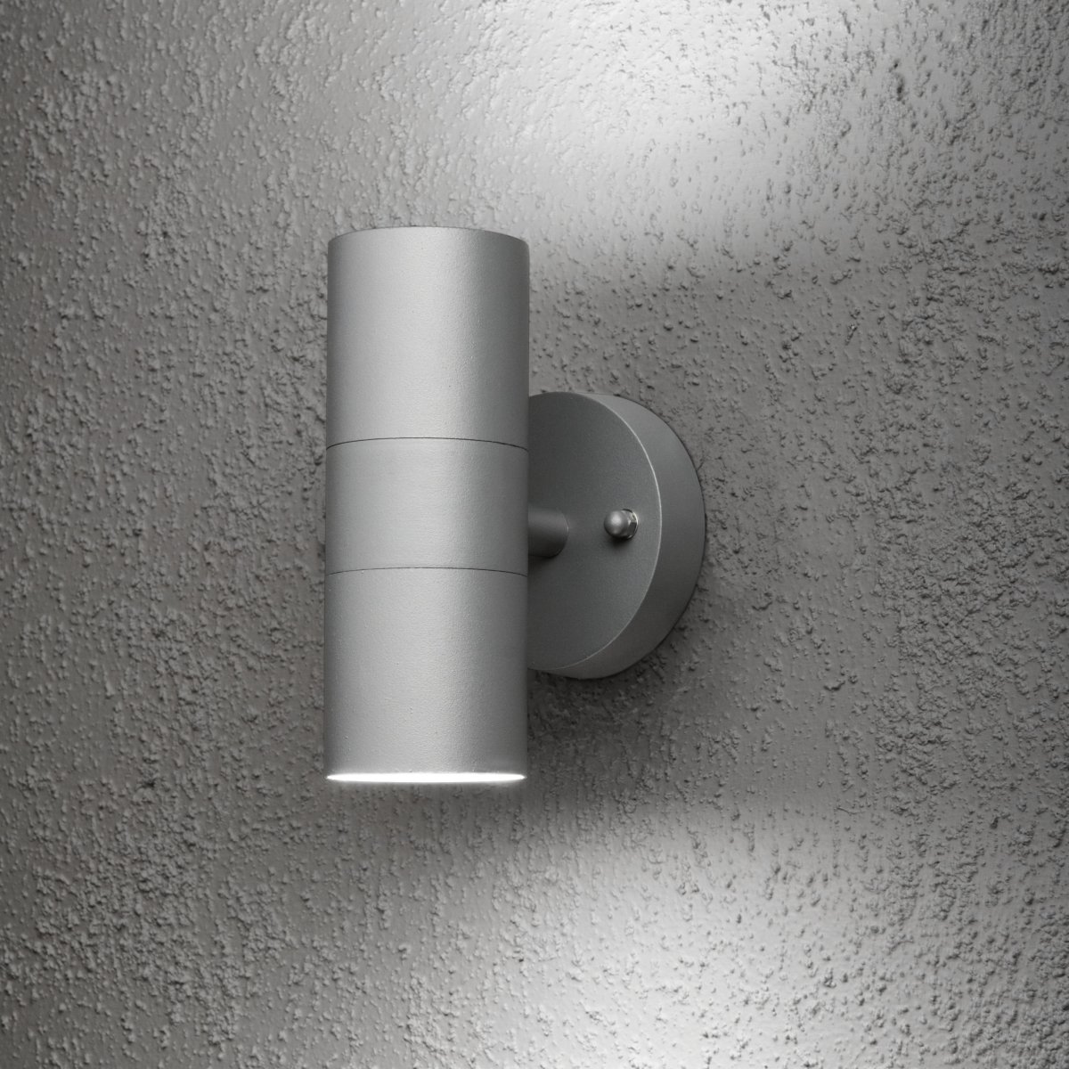 Modena Grå utendørslampe Fra Konstsmide - Lampen sprer lyset b&aring;de oppover og nedover og skaper et dekorativt lysbilde som fremhever fasaden og gir en innbydende f&oslash;lelse utend&oslash;rs.