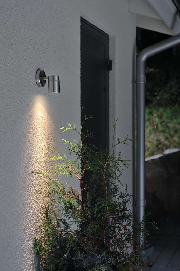 Modena Rustfritt utendørslampe Fra Konstsmide - Med sin runde design og direkte lys er den ideell for å skape en sofistikert atmosfære i entréer og ganger.