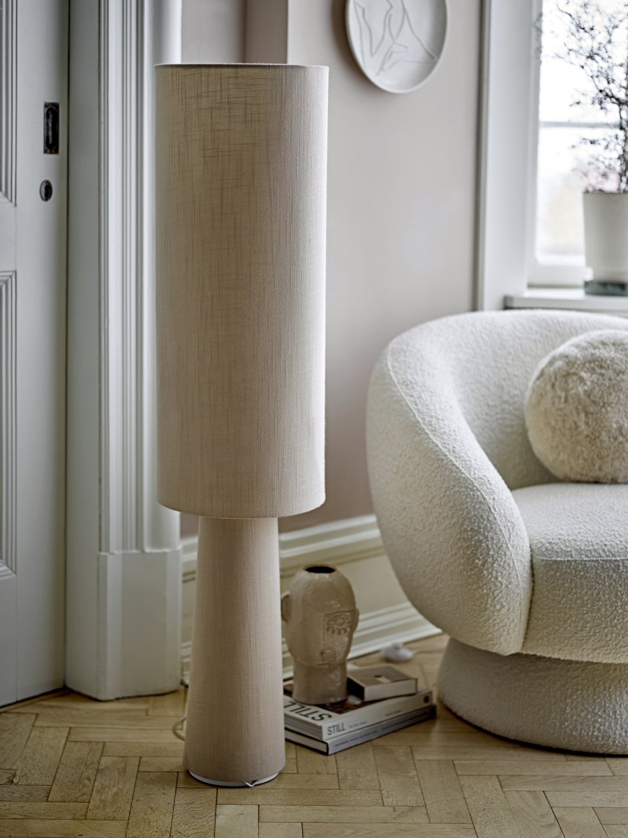 Emmie Natur gulvlampe Fra Bloomingville - Lampen har et enkelt og naturlig design, med b&aring;de lampeskjerm og base i vakkert linstoff, noe som gir en rustikk og koselig f&oslash;lelse.
