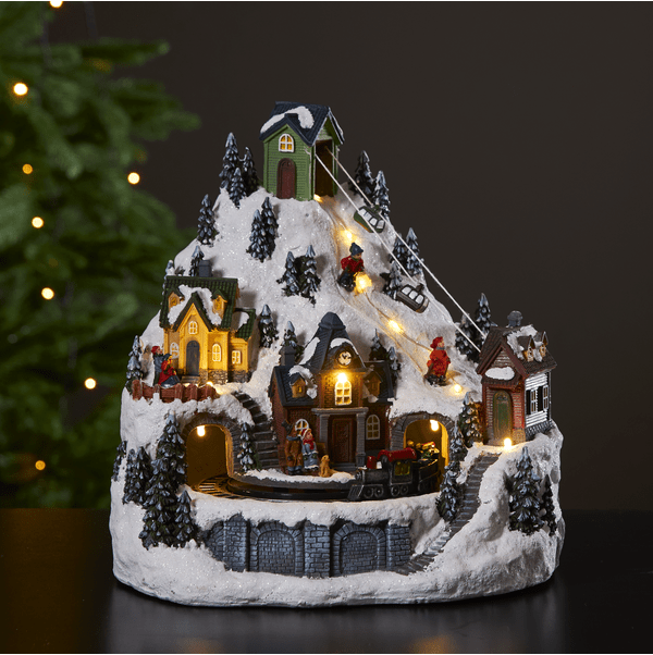 Alpville 25cm Flerfarget Fra Star Trading - Vakker juledekorasjon i form av et dekorativt vinterlandskap med taubane, skil&oslash;pere og togstasjon med roterende tog.