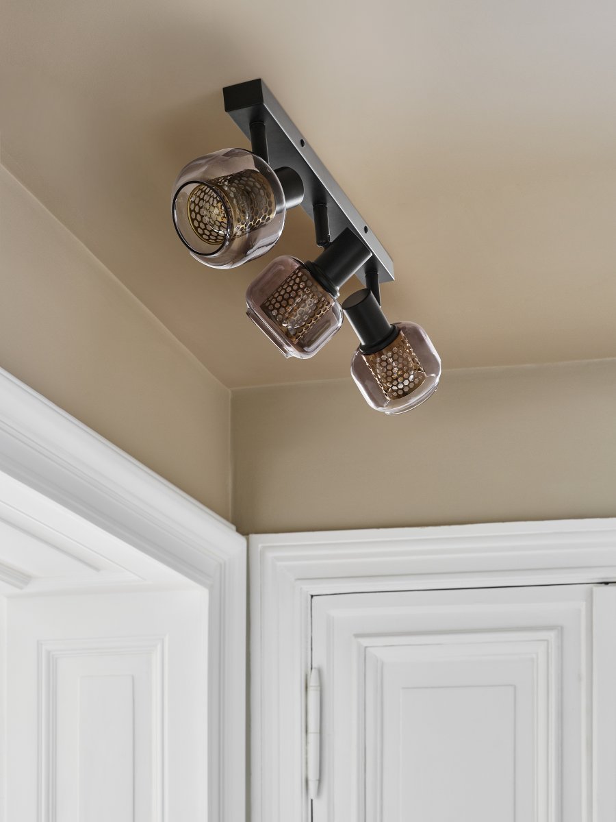 Firefly 3 Svart spotlight Fra Osram - De r&ouml;rliga spotlightsen med sk&auml;rmar av gr&aring;tonat glas i kombination med de guldiga detaljh&ouml;ljet som omfamnar ljusk&auml;llorna bidrar med en elegans till rummet.