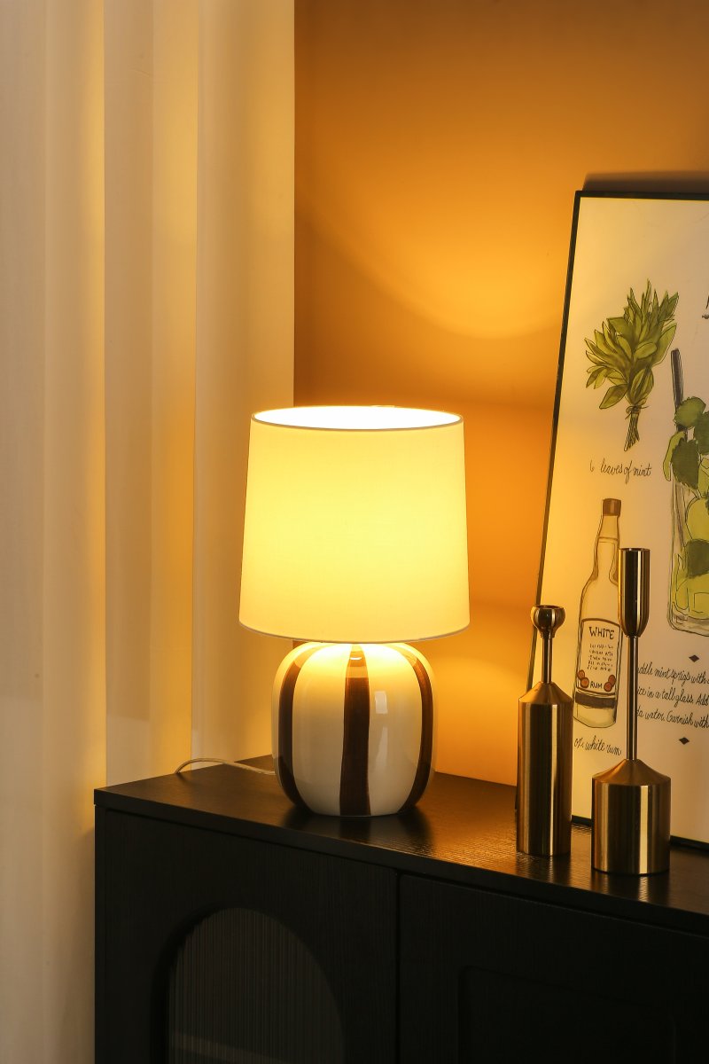 Pholca 38cm Hvit/brun bordlampe Fra Nordic Lighting - Lampefoten er laget av keramikk med en kremhvit base og brune striper som skaper liv og karakter.