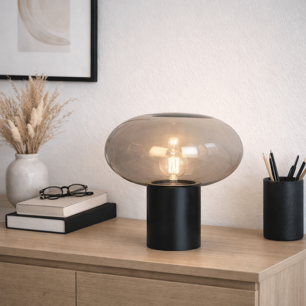 Alba 32cm Svart/Røkt bordlampe Fra Nordic Lighting - Den svarte metallbasen gir et stabilt og elegant uttrykk, mens den r&oslash;ykfargede glassskjermen skaper et mykt og stemningsfullt lys.