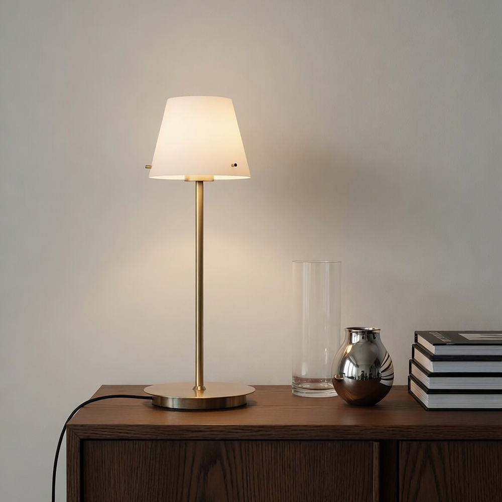 Gil 34cm Sateng messing bordlampe Fra Herstal - Den er laget av metall med en sateng messingfinish og har en hvit glassskjerm som sprer et mykt og behagelig lys.