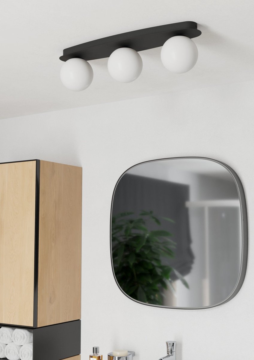 Castrovido 58cm Svart baderomslampe Fra Eglo - Den er laget av svart metall og har tre runde opalglasskugler som sprer et mykt og jevnt lys.