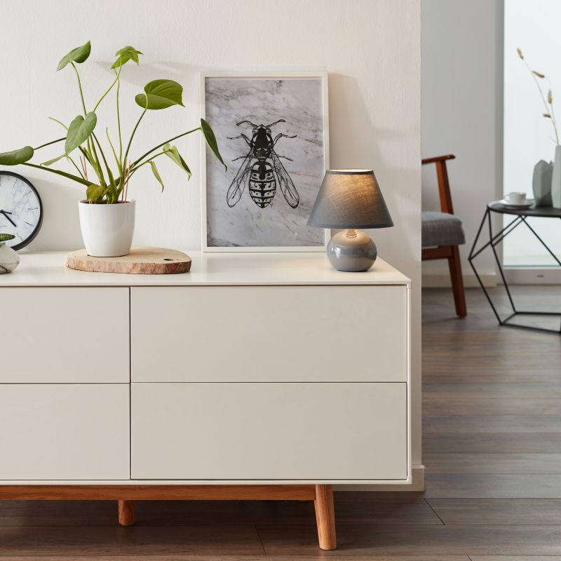 Primo 23cm Mørkegrå bordlampe Fra Brilliant - Den er laget av tekstil og keramikk og gir et behagelig lys.