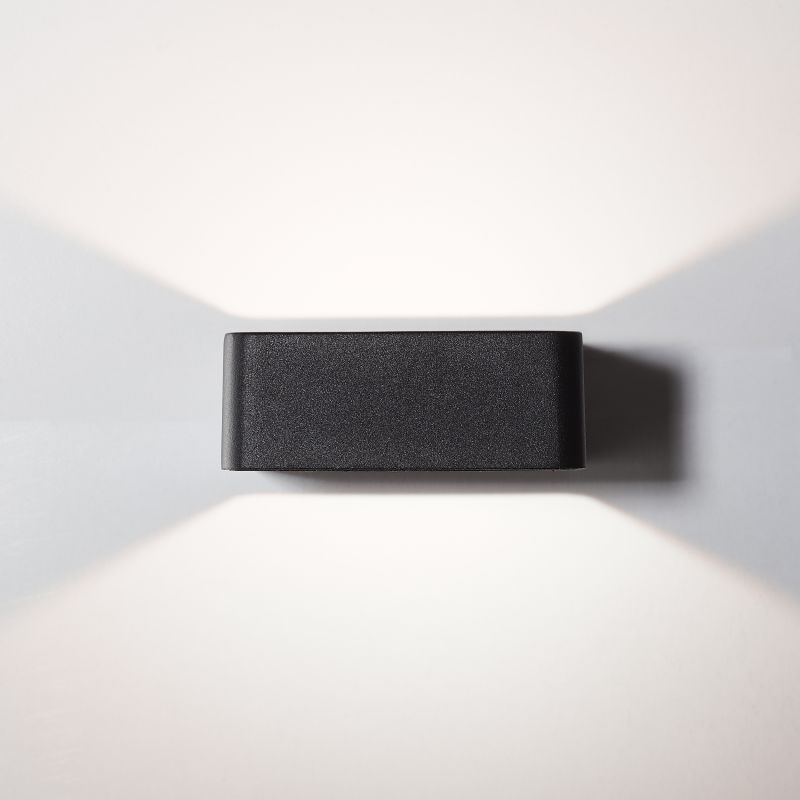 Golda Svart utendørslampe Fra Brilliant - Den fungerer som både praktisk og dekorativ belysning for husfasaden med lys som sprer seg opp og ned langs veggen.
